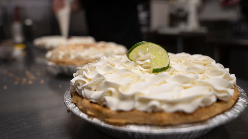 A freshly decorated Key Lime pie rests on a counter in a busy bakery kitchen at Michele's...